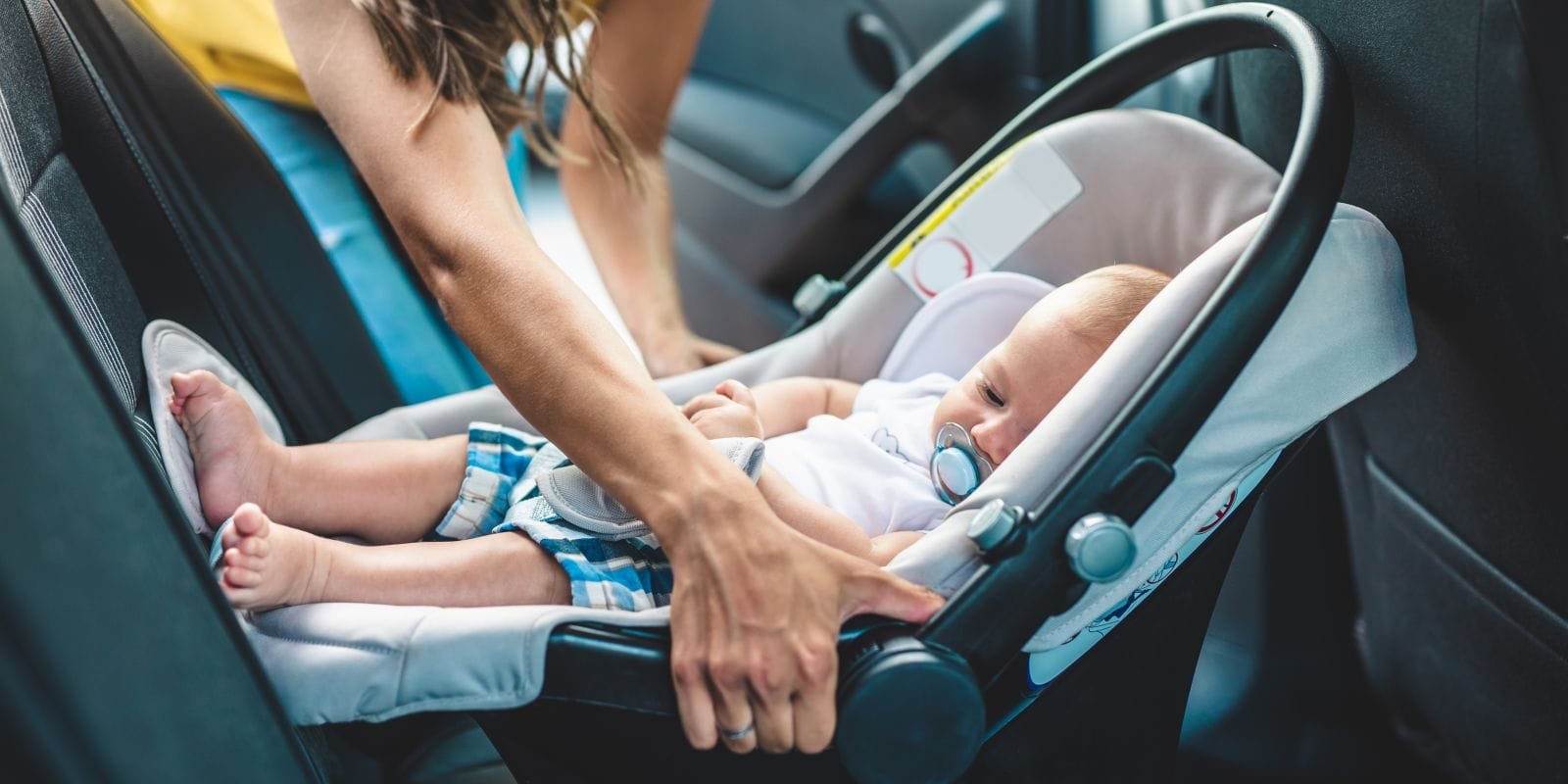 woman putting baby in carseat in the car